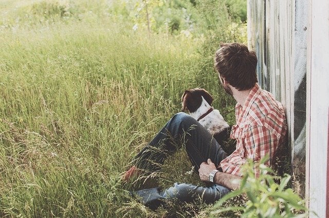 Man and dog sit outside in rural area