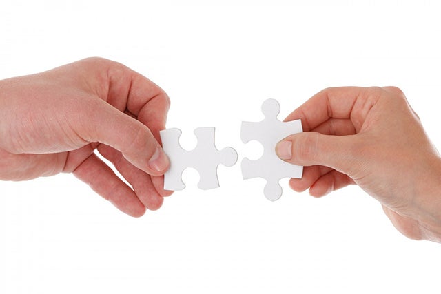 Hands hold puzzle pieces that fit together