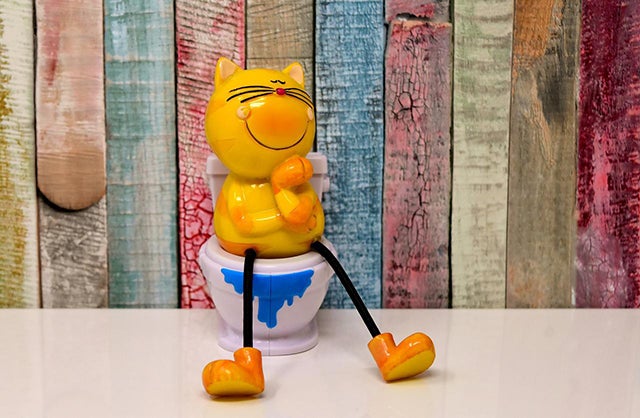 Figurine of an orange cartoon cat sitting on the toilet