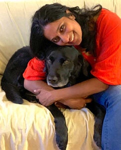 Geraldine D'Silva hugging black dog on couch
