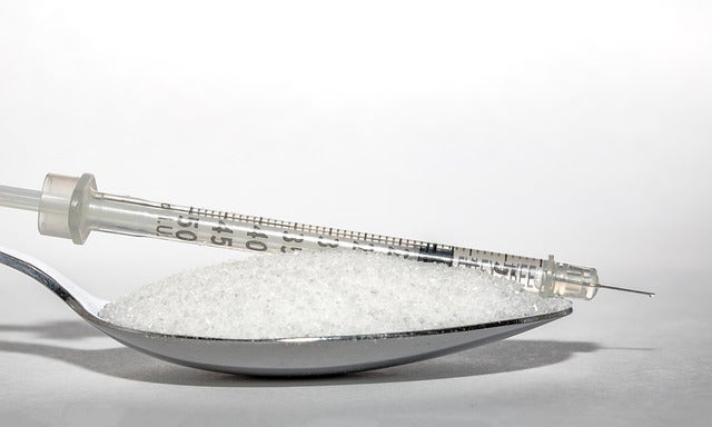 Syringe rests on spoonful of sugar
