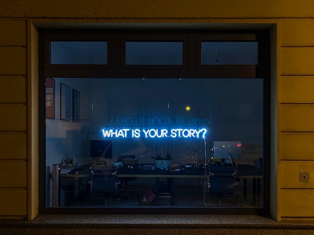 neon sign reads "What is your story?"