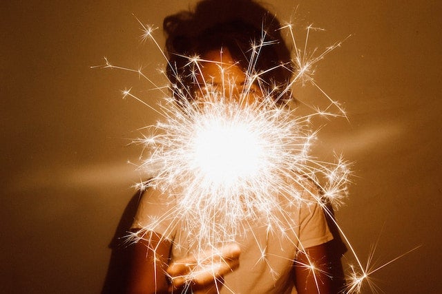 Person holds sparkler shining bright