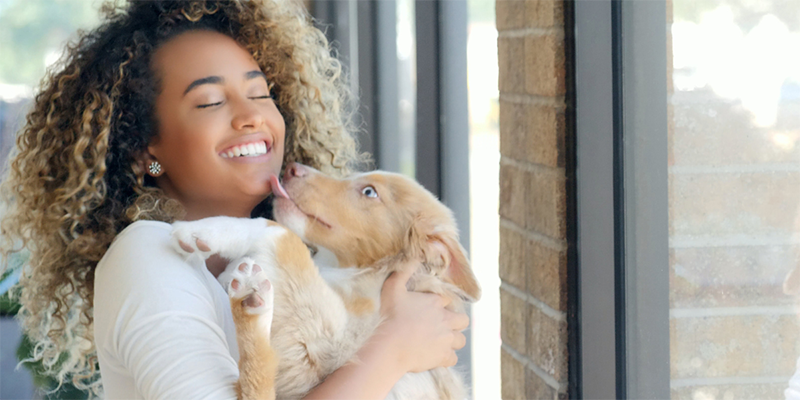 Young BIPOC woman holds happy dog in her arms