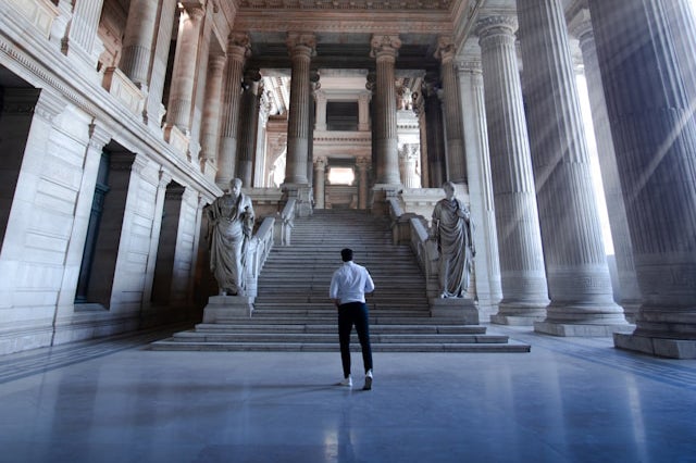 A man prepares to walk up steps inside a courthouse