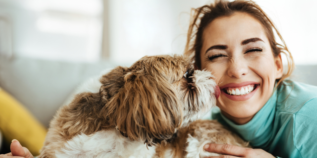 A woman smiles as a dog licks her face