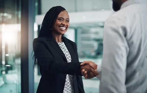 A Black woman wearing a blazer shakes hands