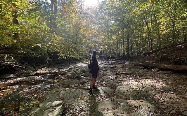 Woman hikes in forested area (Photo via Janna Hicks)